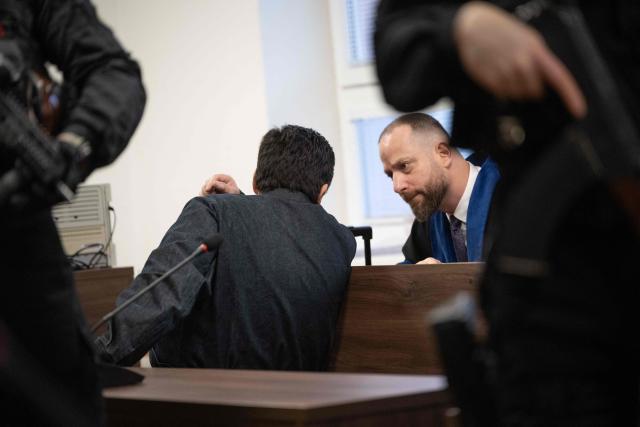 Slovak businessman Marian Kocner (C), accused of ordering the killing of journalist Jan Kuciak and his fiancee Martina Kusnirova, is guarded by armed police and talks to Attorney Marek Para (R) he attends a retrial at Slovak Specialized court in Pezinok, Slovakia, on January 26, 2026. Jan Kuciak, a journalist investigating high-level corruption linked to influential businessmen and top politicians, was shot dead with his fiancee, Martina Kusnirova, both 27, at their home in the village of Velka Maca in February 2018. Their deaths sparked the largest protests in Slovakia since the fall of Communism, leading to the resignation of the government of Robert Fico, although the nationalist prime minister returned to power in 2023. (Photo by Joe Klamar / AFP)
