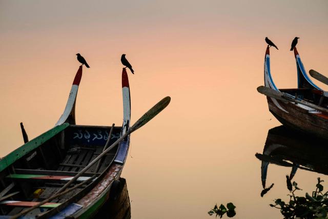 Birds rest on boats in Taungthaman Lake near the U Bein bridge in Mandalay on January 26, 2026. (Photo by ANTHONY WALLACE / AFP)