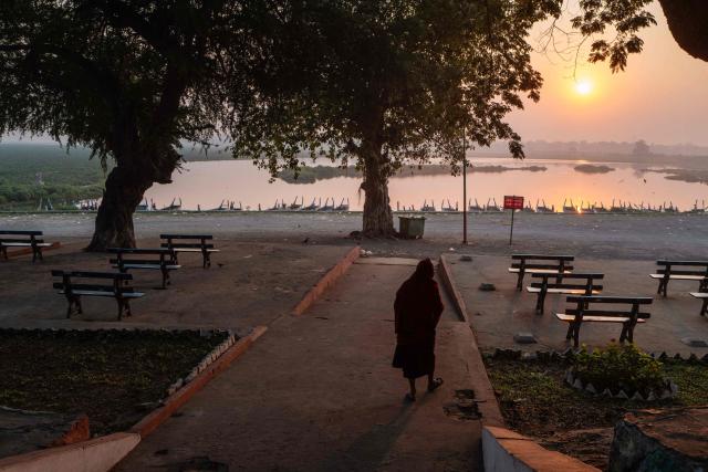A monk walks near the U Bein bridge (not seen) which spans the Taungthaman Lake (back) in Mandalay on January 26, 2026. (Photo by ANTHONY WALLACE / AFP)