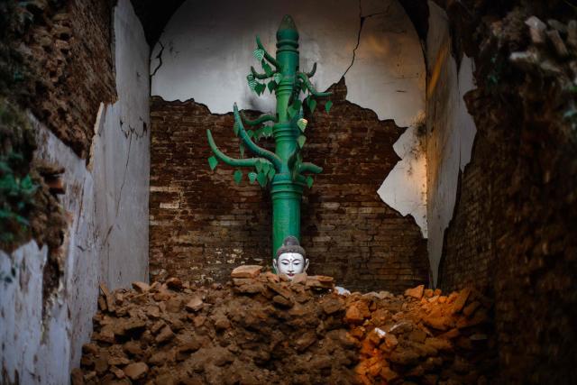 TOPSHOT - A statue of a Buddha is seen amongst the ruins of a temple in Mandalay on January 26, 2026, after if was damaged by an earthquake on March 28 last year, which killed nearly 3,800 people. (Photo by ANTHONY WALLACE / AFP)