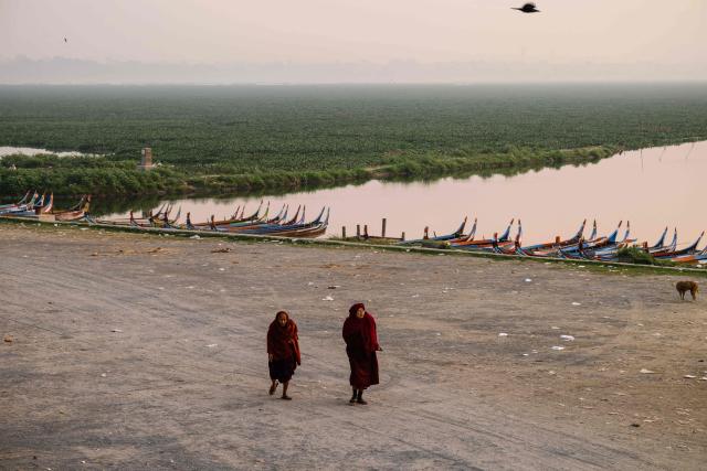 Monks walk near the U Bein bridge (not seen) which spans the Taungthaman Lake in Mandalay on January 26, 2026. (Photo by ANTHONY WALLACE / AFP)