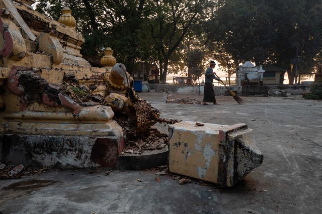 A man sweeps the ground next to the ruins of a temple in Mandalay on January 26, 2026, after if was damaged by an earthquake on March 28 last year, which killed nearly 3,800 people. (Photo by ANTHONY WALLACE / AFP)