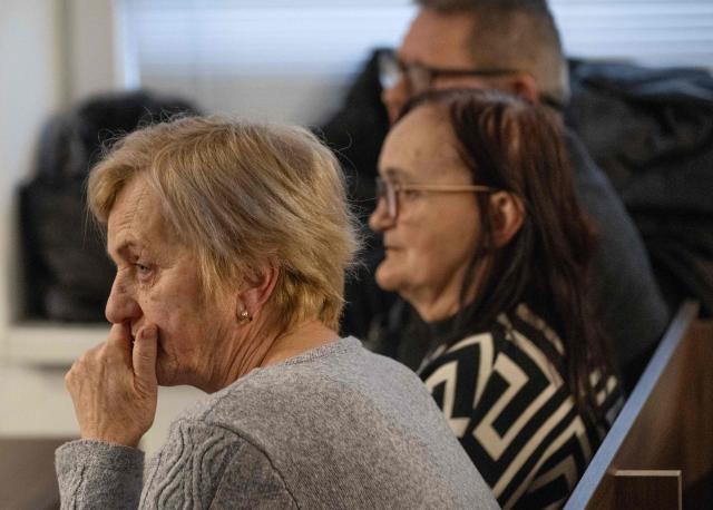 Zlatica Kusnirova (front) mother of Martina Kusnirova, and the parents of Jan Kuciak Jana Kuciakova (C) and Jozef Kuciak (back) attend the retrial of Slovak businessman Marian Kocner (unseen), accused of ordering the killing of journalist Jan Kuciak and his fiancee Martina Kusnirova, is guarded by armed police as he attends a retrial at Slovak Specialized court in Pezinok, Slovakia, on January 26, 2026. Jan Kuciak, a journalist investigating high-level corruption linked to influential businessmen and top politicians, was shot dead with his fiancee, Martina Kusnirova, both 27, at their home in the village of Velka Maca in February 2018. Their deaths sparked the largest protests in Slovakia since the fall of Communism, leading to the resignation of the government of Robert Fico, although the nationalist prime minister returned to power in 2023. (Photo by Joe Klamar / AFP)
