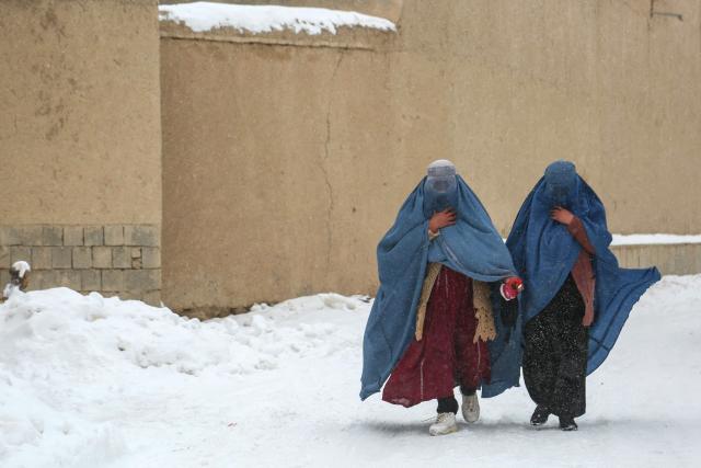 Afghan burqa-clad women walk on a snow-covered street in Ghazni on January 26, 2026. (Photo by Mohammad Faisal NAWEED / AFP)