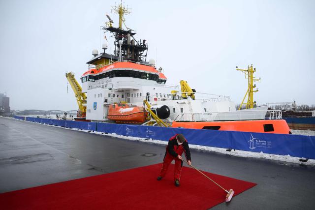 A worker cleans the red carpet in front of the police ship "Neuwerk" of the coast guard prior to the arrival of state leaders for the North Sea Summit on January 26, 2026 in Hamburg, northern Germany. European leaders meet to discuss North Sea energy and security cooperation, but fears over US designs on the Arctic island of Greenland may overshadow the talks. The region has long worried about threats posed by Russia -- but more recently tensions have surged over US President Donald Trump's push for the autonomous territory of Denmark. (Photo by Gregor Fischer / AFP)