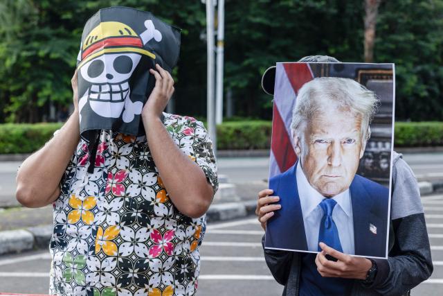 Activists hold a portrait of US President Donald Trump and and a logo of the popular Japanese manga One Piece, a symbol adopted by Gen Z protest movements worldwide, as they demonstrate against US interventionism and modern colonialism in front of the US Embassy in Jakarta on January 26, 2026. (Photo by KRISTIANTO PURNOMO / AFP)