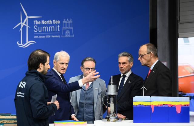 (R-L) German Chancellor Friedrich Merz, Netherland's Prime Minister Dick Schoof, Belgium's Prime Minister Bart de Wever and Norway's Prime Minister Jonas Gahr Store listen to explanations they get from Alexander Sebastian Frank, engineer at the Federal Maritime and Hydrographic Agency (BSH), as they attend the North Sea Summit on January 26, 2026 in Hamburg, northern Germany. European leaders meet to discuss North Sea energy and security cooperation, but fears over US designs on the Arctic island of Greenland may overshadow the talks. The region has long worried about threats posed by Russia -- but more recently tensions have surged over US President Donald Trump's push for the autonomous territory of Denmark. (Photo by Gregor Fischer / AFP)