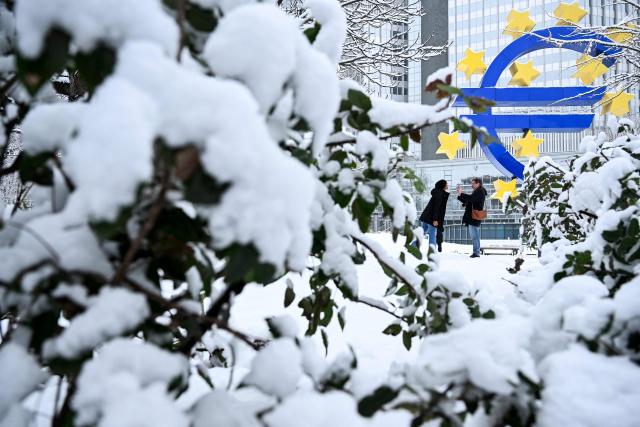 A woman poses for photo in front of the Euro currency logo near the former European Central Bank (ECB) building after snowfall in Frankfurt am Main, western Germany, on January 26, 2026 as the air temperature reached 1 degrees Celsius above zero. (Photo by Kirill KUDRYAVTSEV / AFP)