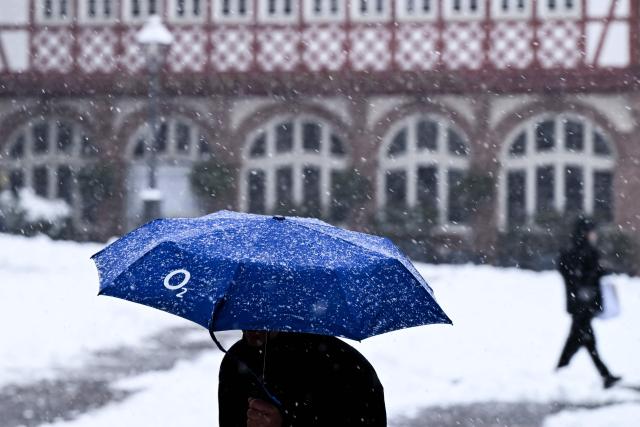 A man with an umbrella walks on the snow-covered Roemer square in Frankfurt am Main, western Germany, on January 26, 2026 as the air temperature reached 1 degrees Celsius above zero. (Photo by Kirill KUDRYAVTSEV / AFP)