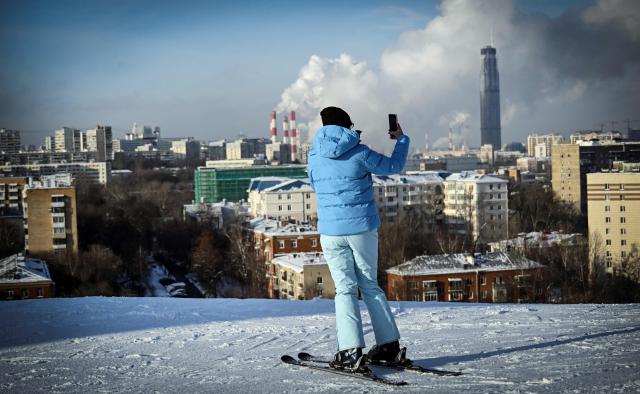 A woman takes a photo on top of a slope at the Kant Ski Club in southern Moscow on January 26, 2026. (Photo by Alexander NEMENOV / AFP)