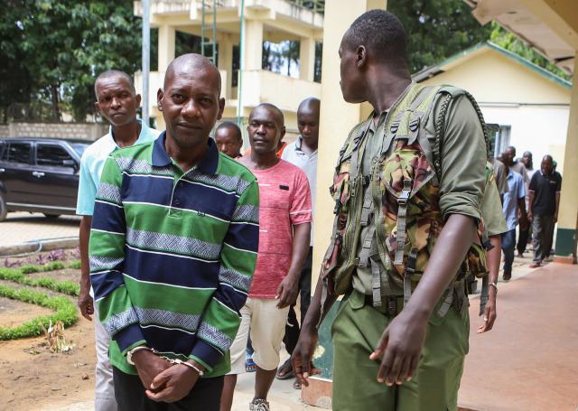 (FILES) Self-proclaimed pastor Paul Nthenge Mackenzie (L) walks surrounded by Kenya Police Officers and other defendants as he appears at the Shanzu Law Courts in Mombasa on January 18, 2024. Kenya said on January 26, 2026 that it will charge self-proclaimed preacher Paul Nthenge Mackenzie, linked to an infamous starvation cult that killed more than 400 people, over a further 52 deaths in a remote village near the coast. (Photo by AFP)
