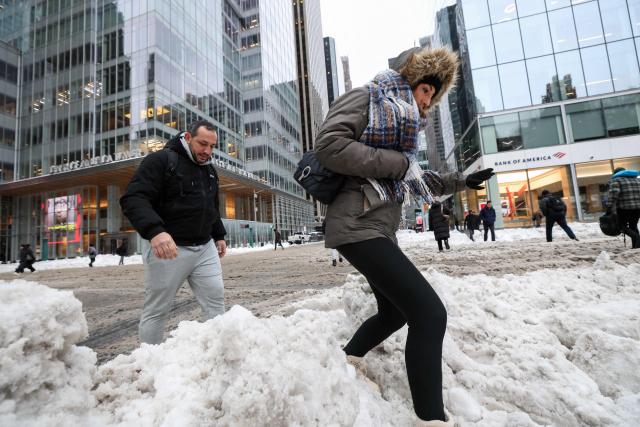 Pedestrians walk through snow as they cross a street in the Manhattan borough of New York City on January 26, 2026. A monster storm barreling across the United States had killed at least 11 people on Monday, prompting warnings to stay off the roads, mass flight cancelations and power outages after a weekend of misery. The storm dumped snow, sleet and freezing rain across swathes of the country from Texas to New England, with temperatures set to fall dangerously low this week. (Photo by TIMOTHY A. CLARY / AFP)
