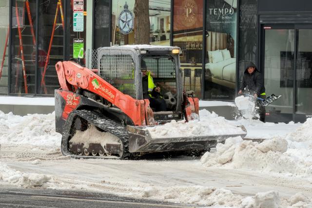 Workers remove snow from a street in Washington, DC, on January 26, 2026. A monster storm barreling across the United States had killed at least 11 people on Monday, prompting warnings to stay off the roads, mass flight cancelations and power outages after a weekend of misery. The storm dumped snow, sleet and freezing rain across swathes of the country from Texas to New England, with temperatures set to fall dangerously low this week. (Photo by Daniel SLIM / AFP)