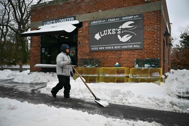 A worker clears snow from a path in the Brooklyn borough of New York City on January 26, 2026. A monster storm barreling across the United States had killed at least 11 people on Monday, prompting warnings to stay off the roads, mass flight cancelations and power outages after a weekend of misery. The storm dumped snow, sleet and freezing rain across swathes of the country from Texas to New England, with temperatures set to fall dangerously low this week. (Photo by ANGELA WEISS / AFP)