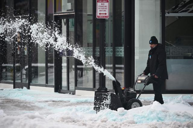 A worker clears snow from a sidewalk in front of an office building in Washington, DC on January 26, 2026. A monster storm barreling across the United States had killed at least 11 people on Monday, prompting warnings to stay off the roads, mass flight cancelations and power outages after a weekend of misery. The storm dumped snow, sleet and freezing rain across swathes of the country from Texas to New England, with temperatures set to fall dangerously low this week. (Photo by Mandel NGAN / AFP)
