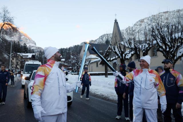 Torchbearers take part in the relay of the Olympic flame in Cortina d'Ampezzo on January 26, 2026. (Photo by Odd ANDERSEN / AFP)