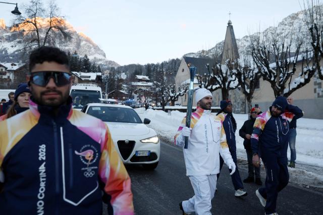 A torchbearer takes part in the relay of the Olympic flame in Cortina d'Ampezzo on January 26, 2026. (Photo by Odd ANDERSEN / AFP)