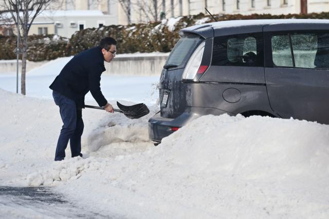 A driver digs his car out from the snow in Washington, DC on January 26, 2026. A monster storm barreling across the United States had killed at least 11 people on Monday, prompting warnings to stay off the roads, mass flight cancelations and power outages after a weekend of misery. The storm dumped snow, sleet and freezing rain across swathes of the country from Texas to New England, with temperatures set to fall dangerously low this week. (Photo by Mandel NGAN / AFP)