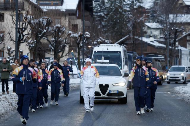 A torchbearer takes part in the relay of the Olympic flame in Cortina d'Ampezzo on January 26, 2026. (Photo by Odd ANDERSEN / AFP)