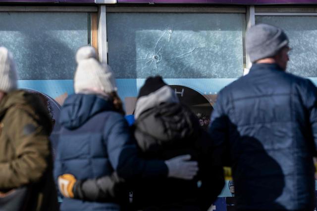 Two women hug as they visit a makeshift memorial for Alex Pretti next to window panels showing two gun perforations on January 26, 2026 that according to the business owner said were made when Alex Pretti was gunned down by federal agents in Minneapolis, Minnesota on January 24, 2026. On January 24, federal agents shot and killed Alex Pretti, a 37-year-old ICU nurse, while scuffling with him on an icy roadway in Minneapolis, less than three weeks after an immigration officer fired on Renee Good, also 37, killing her in her car. US President Donald Trump blamed their deaths on Democratic "chaos," as his administration faced intensifying pressure over its mass immigration crackdown in Minneapolis. (Photo by ROBERTO SCHMIDT / AFP)