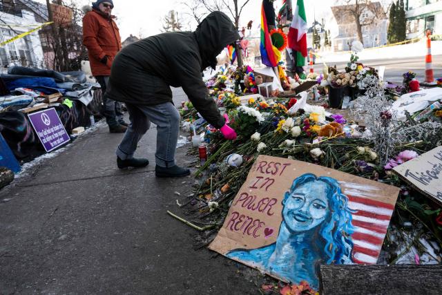 A woman places flowers on January 26, 2026 at a makeshift memorial for Renee Good who was gunned down by federal agents in Minneapolis, Minnesota on January 7, 2026. On January 24, federal agents shot and killed Alex Pretti, a 37-year-old ICU nurse, while scuffling with him on an icy roadway in Minneapolis, less than three weeks after an immigration officer fired on Renee Good, also 37, killing her in her car. US President Donald Trump blamed their deaths on Democratic "chaos," as his administration faced intensifying pressure over its mass immigration crackdown in Minneapolis. (Photo by ROBERTO SCHMIDT / AFP)