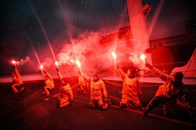 TOPSHOT - French skipper Alexia Barrier and crew members celebrate holding lit flares upon their arrival at Brest harbour on the Ultim multihull Idec Sport after crossing the finish line of the Jules Verne Trophy, off the coast of Brest, Brittany, on January 26, 2026. French skipper Alexia Barrier (The Famous Project) and her six crew members completed on January 26, 2026, off the coast of Brest, the first non-stop round-the-world voyage in a maxi-trimaran with an all-female crew, her team announced. (Photo by Loic VENANCE / AFP)