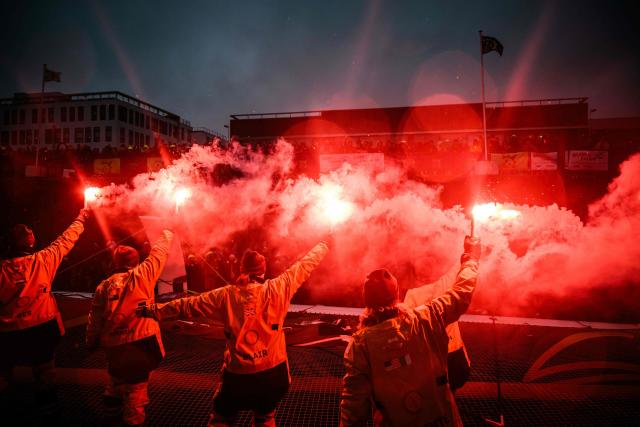 French skipper Alexia Barrier and crew members celebrate holding lit flares upon their arrival at Brest harbour on the Ultim multihull Idec Sport after crossing the finish line of the Jules Verne Trophy, off the coast of Brest, Brittany, on January 26, 2026. French skipper Alexia Barrier (The Famous Project) and her six crew members completed on January 26, 2026, off the coast of Brest, the first non-stop round-the-world voyage in a maxi-trimaran with an all-female crew, her team announced. (Photo by Loic VENANCE / AFP)