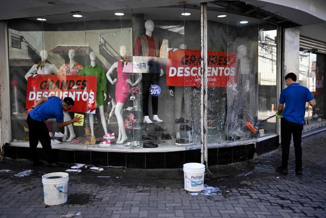 Two employees wash the windows of a warehouse in the historic center of Tegucigalpa on January 26, 2026, ahead of the inauguration of President-elect Nasry Asfura. Asfura, a conservative businessman who was declared the winner of Honduras's presidential election on December 24, weeks after a tight race marred by delays and allegations of fraud, will take office on January 27, 2026. (Photo by JOHAN ORDONEZ / AFP)