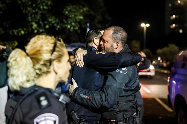 Israeli police officers hug as they pay their respects outside of the Abu Kabir Forensic Institute, as the body of last Israeli  hostage arrives in Tel Aviv on January 26, 2026. The remains of the last hostage held in Gaza, Ran Gvili, were brought back to Israel on January 26, closing the chapter on a painful saga that has kept Israeli society on edge ever since Hamas's unprecedented October 7, 2023 attack. (Photo by ilia yefimovich / AFP)