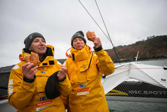 Crew members of The Famous Project eat French pastries pains au chocolat as they celebrate and sail towards the Brest harbour after crossing the finish line of the Jules Verne Trophy on the Ultim multihull Idec Sport, off the coast of Brest, Brittany, on January 26, 2026. French skipper Alexia Barrier (The Famous Project) and her six crew members completed on January 26, 2026, off the coast of Brest, the first non-stop round-the-world voyage in a maxi-trimaran with an all-female crew, her team announced. The Jules Verne Trophy is a prize for the fastest crewed, unassisted and non-stop circumnavigation of the world on any type of yacht. (Photo by Loic VENANCE / AFP)
