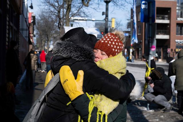 Two women hug at a makeshift memorial in the area where Alex Pretti was shot dead by federal immigration agents in Minneapolis, Minnesota, on January 26, 2026. On January 24, federal agents shot and killed Alex Pretti, a 37-year-old ICU nurse, while scuffling with him on an icy roadway in Minneapolis, less than three weeks after an immigration officer fired on Renee Good, also 37, killing her in her car. US President Donald Trump blamed their deaths on Democratic "chaos," as his administration faced intensifying pressure over its mass immigration crackdown in Minneapolis. (Photo by ROBERTO SCHMIDT / AFP)