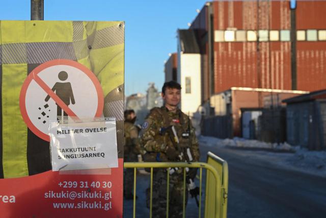 A Danish soldier stands at a checkpoint in the harbor of Nuuk, Greenland, on January 26, 2026. HDMS Knud Rasmussen (P570) and HDMS Ejnar Mikkelsen (P571), Royal Danish Navy patrol vessels, are moored in the harbour. They are employed to exercise Danish sovereignty in the waters around the Faroe Islands and Greenland. (Photo by Ina FASSBENDER / AFP)