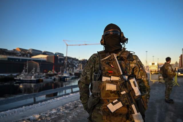 A Danish soldier stands at a checkpoint in the harbor of Nuuk, Greenland, on January 26, 2026. HDMS Knud Rasmussen (P570) and HDMS Ejnar Mikkelsen (P571), Royal Danish Navy patrol vessels, are moored in the harbour. They are employed to exercise Danish sovereignty in the waters around the Faroe Islands and Greenland. (Photo by Ina FASSBENDER / AFP)