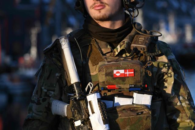 A Danish soldier stands at a checkpoint in the harbor of Nuuk, Greenland, on January 26, 2026. HDMS Knud Rasmussen (P570) and HDMS Ejnar Mikkelsen (P571), Royal Danish Navy patrol vessels, are moored in the harbour. They are employed to exercise Danish sovereignty in the waters around the Faroe Islands and Greenland. (Photo by Ina FASSBENDER / AFP)