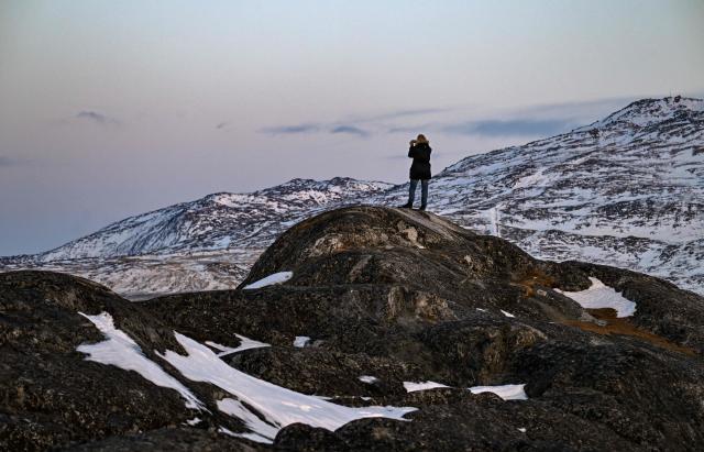 A man takes a photo at the coastline in Nuuk, Greenland, on January 26, 2026. (Photo by Ina FASSBENDER / AFP)
