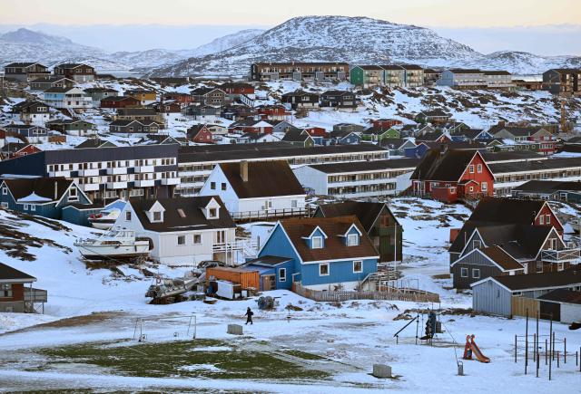 A woman walks in front of a soccer field in a snowy residential area in the city of Nuuk, western Greenland, on January 26, 2026. (Photo by Ina FASSBENDER / AFP)