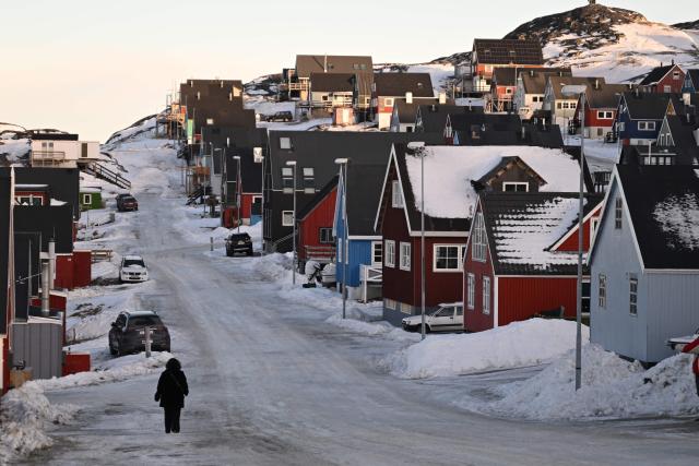 A woman walks at a snowy residential area in the city of Nuuk, western Greenland, on January 26, 2026. (Photo by Ina FASSBENDER / AFP)