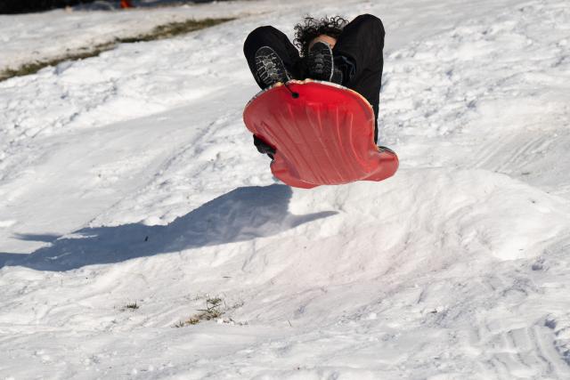 A person sleds outside the US Capitol in Washington, DC, on January 26, 2026, following a significant snow storm. Millions of Americans were facing dangerously cold temperatures in the wake of a massive winter storm that whipped snow and ice across the country, knocking out power and paralyzing transportation. A frigid, potentially life-threatening Arctic air mass threatened to delay clean-up as municipalities from New Mexico to Maine tried to dig out following the storm, which dropped a vicious cocktail of heavy snow and wind along with freezing rain and sleet. (Photo by SAUL LOEB / AFP)