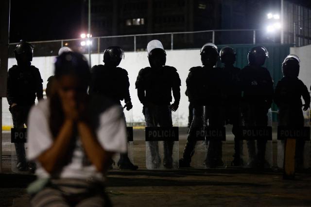 Members of the national police stand guard outside Zone 7 of the Bolivarian National Police (PNB) in the Sucre municipality of the Metropolitan District of Caracas (DMC) on January 26, 2026. More than 100 political prisoners were freed on the eve in Venezuela, where detainees are slowly being released under pressure from the United States, the non-governmental organization Foro Penal said. (Photo by Pedro MATTEY / AFP)