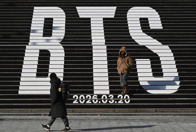 (FILES) Pedestrians walk along the stairs displayed with the BTS logo and release date of BTS' 2026 album at Gwanghwamun Square in Seoul on January 14, 2026. Mexico's President Claudia Sheinbaum declared on January 26, 2026, that "nearly a million young people" had vied for one of the coveted 150,000 tickets to K-pop megastars BTS's Mexican gigs and said she wrote to South Korea's President Lee Jae Myung to ask that he "bring the acclaimed K-pop artists more often" to her country. Sheinbaum said she had also asked Ocesa, the promoter of the shows in Mexico, about the possibility of organizing more dates, but received a negative answer. BTS will perform three dates in Mexico City in May 2026. (Photo by Jung Yeon-je / AFP)