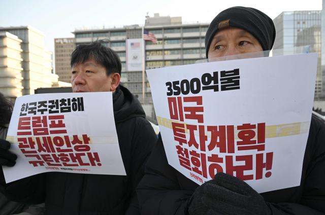 Protesters hold placards reading "We condemn Trump's tariff hikes!" during a rally condemning Trump's plans to raise tariffs on South Korea in front of the US embassy in Seoul on January 27, 2026. US President Donald Trump said January 26, that he would raise tariffs on South Korean goods including autos, lumber and pharmaceuticals, accusing the country of not living up to an earlier trade pact struck with Washington. (Photo by Jung Yeon-je / AFP)