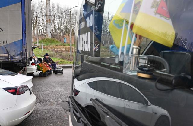 A Moldovan man sells apples and grapes to people waiting to enter Ukraine at the Moldova–Ukraine border crossing point of Palanca–Maiaki in the village of Palanca on January 6, 2026. Since the start of the conflict in February 2022, Moldova has recorded dozens of violations of its airspace, and several Russian missiles and drones have crashed on its territory. The latest, a Shahed drone carrying 50 kilograms of explosives, fell 12 kilometres northwest of Palenca on January 22 without causing any damage. In November, the former Soviet republic, which is neither a member of the European Union nor NATO, was forced to close its borders. (Photo by Daniel MIHAILESCU / AFP)