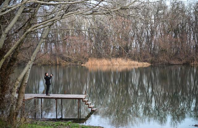 A woman standing on a pontoon takes a picture of the Nistru River, few kilometres from the border crossing point Palanca-Maiaki between Moldova and Ukraine, in Tudora village. Since the start of the conflict in February 2022, Moldova has recorded dozens of violations of its airspace, and several Russian missiles and drones have crashed on its territory. The latest, a Shahed drone carrying 50 kilograms of explosives, fell 12 kilometres northwest of Palenca on January 22 without causing any damage. In November, the former Soviet republic, which is neither a member of the European Union nor NATO, was forced to close its borders. (Photo by Daniel MIHAILESCU / AFP)