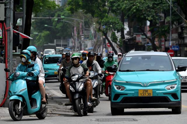 (FILES) Vinfast electric vehicles are pictured on a street in Hanoi on July 31, 2025. Vietnam's first homegrown electric car manufacturer is partnering with Israeli AI firm Autobrains to upgrade its autonomous driving technology and launch a lower-cost "robo-car" system, VinFast said on January 27, 2026. (Photo by Nhac NGUYEN / AFP)
