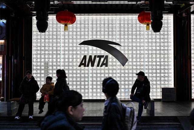 People walk past an Anta store in the Huangpu district of Shanghai on January 27, 2026. Chinese athletic goods giant Anta Sports will buy a controlling stake in historic German sportswear brand Puma for 1.79 billion USD, a stock exchange filing showed, as it expands its international presence. (Photo by Hector RETAMAL / AFP)