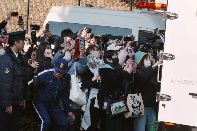 Panda lovers wave goodbye to a truck believed to be carrying the twin pandas upon a departure from Ueno Zoo in Tokyo on January 27, 2026, heading towards their return to China. (Photo by Kazuhiro NOGI / AFP)