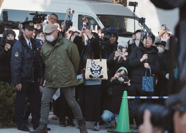 Panda lovers wait at the gates to say goodbye to the twin pandas as they depart from Ueno Zoo in Tokyo on January 27, 2026, heading towards their return to China. (Photo by Kazuhiro NOGI / AFP)