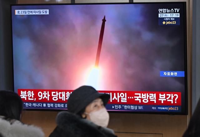 People sit in front of a television screen showing a news broadcast with file footage of a North Korean missile test, at a train station in Seoul on January 27, 2026. North Korea fired at least two ballistic missiles towards the Sea of Japan, a day after a top Pentagon official visited the peninsula and hailed Washington's "model ally" in the South. (Photo by Jung Yeon-je / AFP)