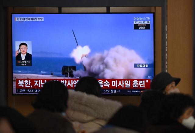 People sit in front of a television screen showing a news broadcast with file footage of a North Korean missile test, at a train station in Seoul on January 27, 2026. North Korea fired at least two ballistic missiles towards the Sea of Japan, a day after a top Pentagon official visited the peninsula and hailed Washington's "model ally" in the South. (Photo by Jung Yeon-je / AFP)