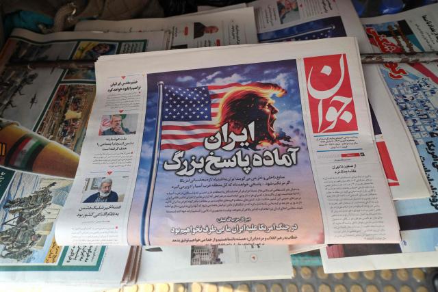 A photograph shows a newspaper with a headline in Persian reading “Iran is ready for a big response” at a kiosk in Tehran on January 27, 2026. A US naval strike group led by an aircraft carrier has deployed to Middle Eastern waters, the United States said on January 26, 2026, as Tehran warned it was ready to hit back at any American attack launched in response to a crackdown on anti-government protests. (Photo by ATTA KENARE / AFP)